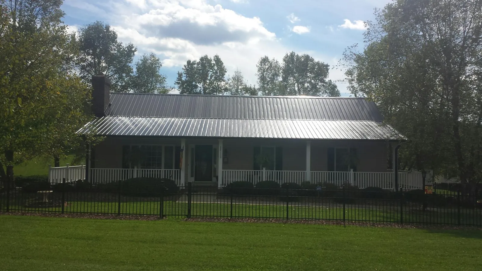 Gray metal roof on a brick ranch with a full width front porch — Gutter Guard Installation work by our crew in Ashford
